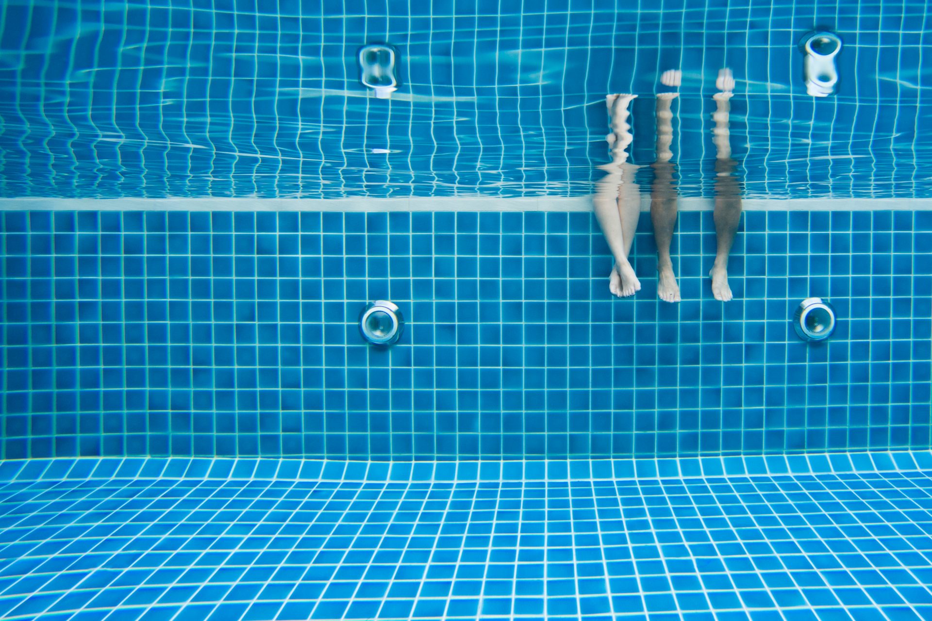 Funny underwater family legs in swimming pool, vacation and sport concept