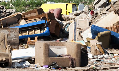 Old furniture at the garbage dump in focus, nature and blue sky in the background